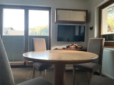 a dining room with a table and chairs and a television at Apartments Katja in Kranjska Gora
