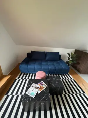 a living room with a blue couch and a rug at AvantGarden in Bled