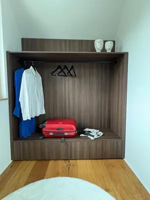 a wooden shelf with a red suitcase and clothes at AvantGarden in Bled