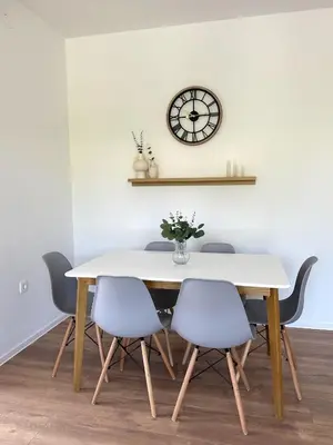 a dining room table with chairs and a clock on the wall at Adria Apartment in Spodnje Škofije