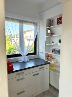 a kitchen with white cabinets and a window at Adria Apartment in Spodnje Škofije