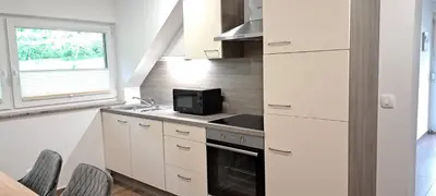 a kitchen with white cabinets and a sink and a microwave at Apartmaji Božiček in Podčetrtek