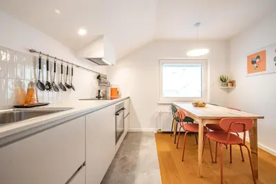 a kitchen with white cabinets and a wooden table at Strato Apartment in Kočevje
