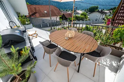 a wooden table and chairs on a balcony at Strato Apartment in Kočevje