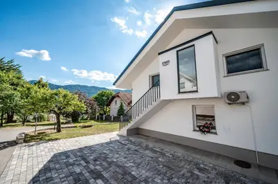 a white house with a staircase and a window at Strato Apartment in Kočevje