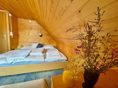 a bedroom with a bed in a wooden room at Vacation cottage house Enya in Koprivnik v Bohinju