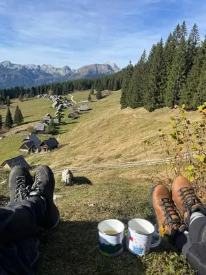 a person sitting on top of a hill with two cups at Vacation cottage house Enya in Koprivnik v Bohinju