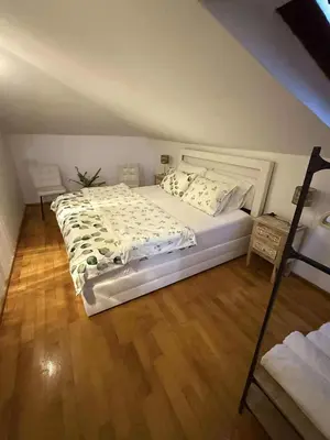 a bedroom with a large white bed and a wooden floor at Apartma Morizna in Kobarid