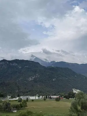 a green field with mountains in the background at Apartma Morizna in Kobarid