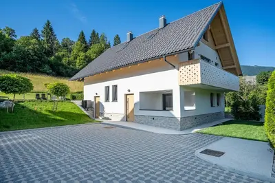 a white house with a black roof and a driveway at Hiša PolajnArh in Bohinj