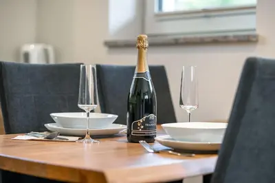 a bottle of champagne sitting on a wooden table with glasses at Hiša PolajnArh in Bohinj