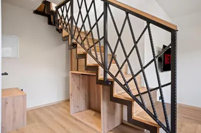 a wooden staircase with black railings in a room at Hiša PolajnArh in Bohinj