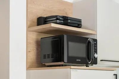 a microwave sitting on a shelf next to a microwave oven at Hiša PolajnArh in Bohinj