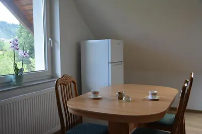 a wooden table with chairs and a white refrigerator at Apartma Rebeka in Zgornje Gorje