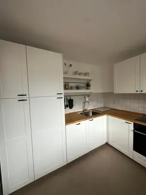 a white kitchen with white cabinets and a sink at Pinus Alpinus Apartments in Bovec