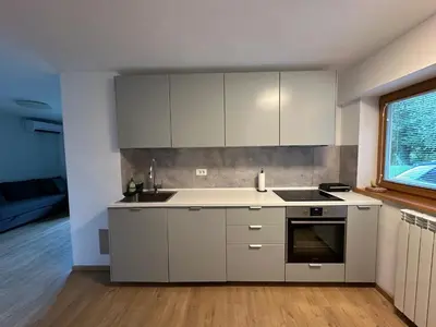 a kitchen with white cabinets and a sink and a window at Pinus Alpinus Apartments in Bovec