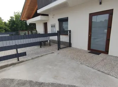 a white house with a door and a fence at Družinski apartmaji Judnič in Adlešiči