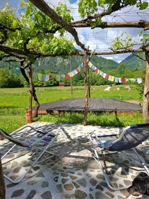 a chair sitting in the shade of a tree with flags at Kamer Luna in Log Čezsoški