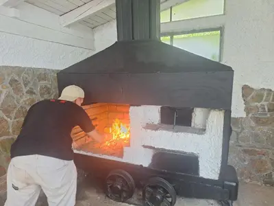 a man putting a fire in a brick oven at Vila Anton in Dobrna