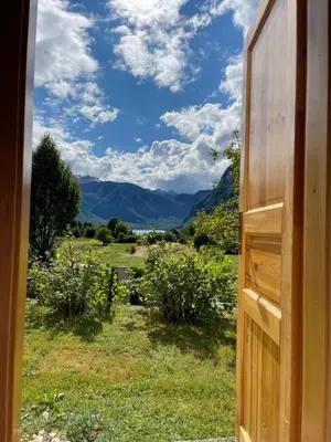 a door opening to a field with mountains in the background at Vintage Lake House Bohinj in Bohinj