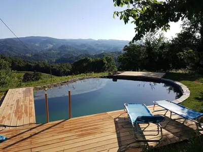 a pool with two chairs next to a wooden deck at Holiday home with 2 bedrooms in Zgornja Kungota