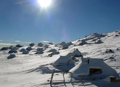 a snow covered mountain with the sun in the sky at Apartment Arpa in Ljubljana