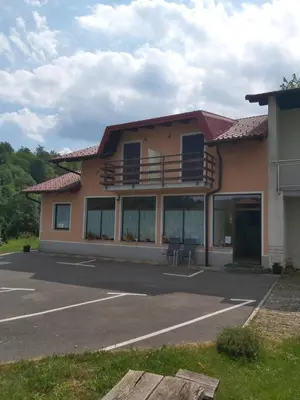a building with a balcony in a parking lot at Rooms Zagon in Postojna