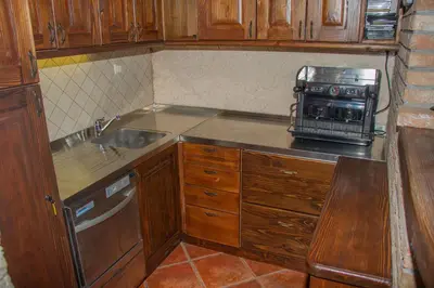 a kitchen with wooden cabinets and a sink and a microwave at Zidanica Krošelj in Raka