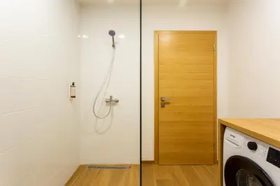 a shower with a glass door next to a washing machine at Sunny Green Escape in Lesce