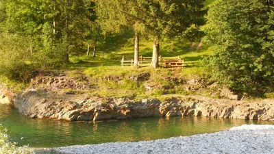 a bench sitting on a hill next to a river at Apartments Savinja in Luče