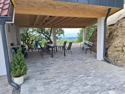 a patio with a table and chairs and a stone wall at En hribček in Ptujska Gora