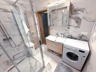 a bathroom with a sink and a washing machine at L Apartment II in Maribor