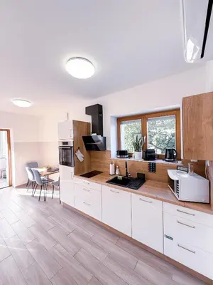 a kitchen with white cabinets and a table with chairs at L Apartment II in Maribor
