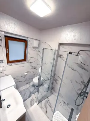 a white bathroom with a shower and a sink at L Apartment II in Maribor