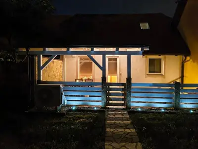 a house with a blue fence in front of it at night at Hiška Maša in Čatež ob Savi