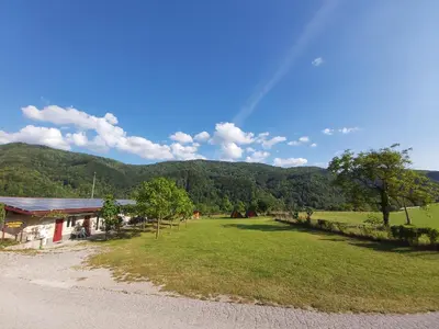 a view of a farm with a field and a building at Apartments Petrin in Tolmin