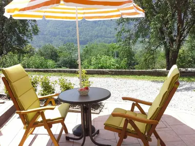 two chairs and a table with an umbrella on a patio at Apartment Zadraga in Tolmin