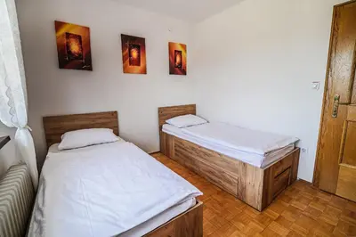 two twin beds in a room with a door at B&B Apartment Racman in Brežice