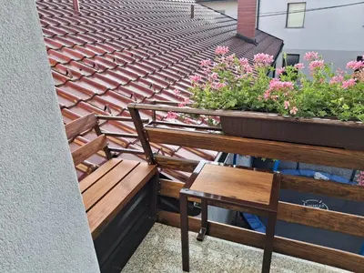 a bench and a chair on a balcony with flowers at Apartma Jasen in Ilirska Bistrica