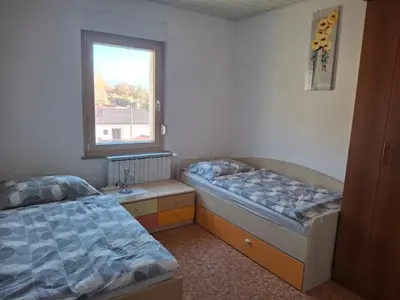 two beds in a room with a window at Apartma Jasen in Ilirska Bistrica