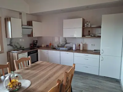 a kitchen with white cabinets and a wooden table at Apartma Jasen in Ilirska Bistrica