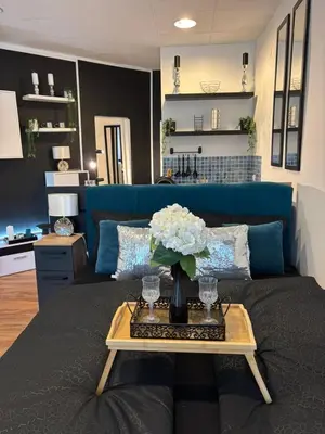 a living room with a blue couch and a table with flowers at Studio Lent Riverstay in Maribor