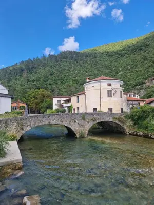 a stone bridge over a river in a town at Apartma Zeleni mir in Dobravlje