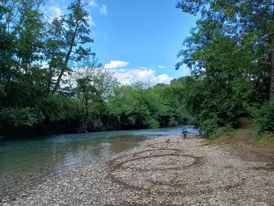 a person riding a bike on the shore of a river at Apartma Zeleni mir in Dobravlje