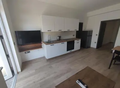 a kitchen with white cabinets and a flat screen tv at Družinski apartmaji Judnič in Adlešiči