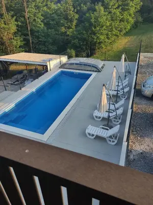 a swimming pool with two chairs and umbrellas at Družinski apartmaji Judnič in Adlešiči