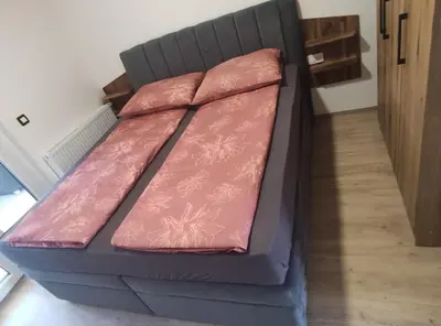 a futon bed in a room with pink sheets at Družinski apartmaji Judnič in Adlešiči