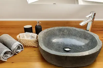 a stone sink on a wooden counter with towels at Lux House Natura with Sauna & Hot Tub