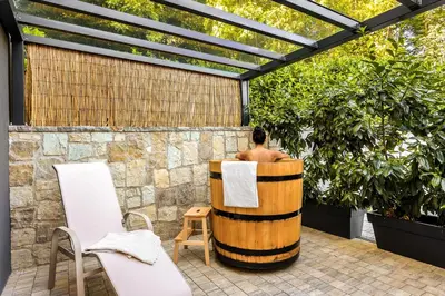 a man sitting in a barrel on a patio at Lux House Natura with Sauna & Hot Tub
