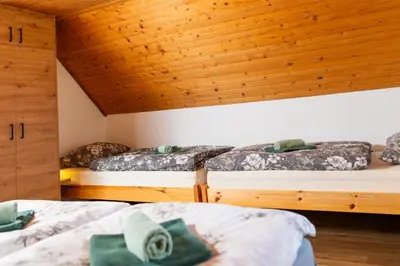 three beds in a room with wooden ceilings at Hiška Nives in Krstenica